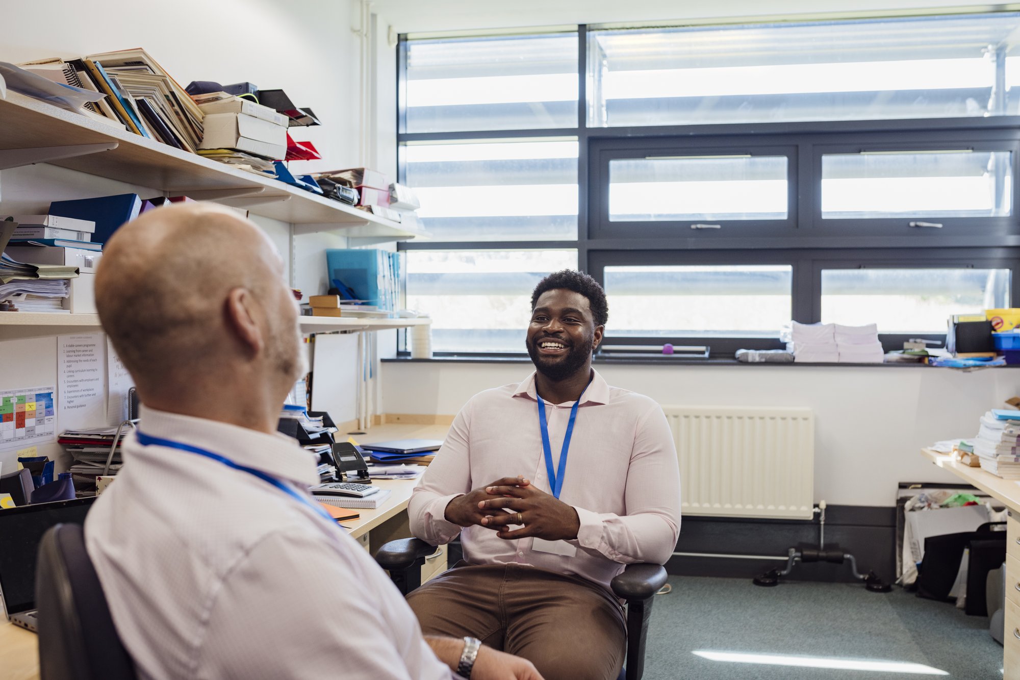 2 adult male teachers laughing in school office 2 adult male teachers laughing in school office