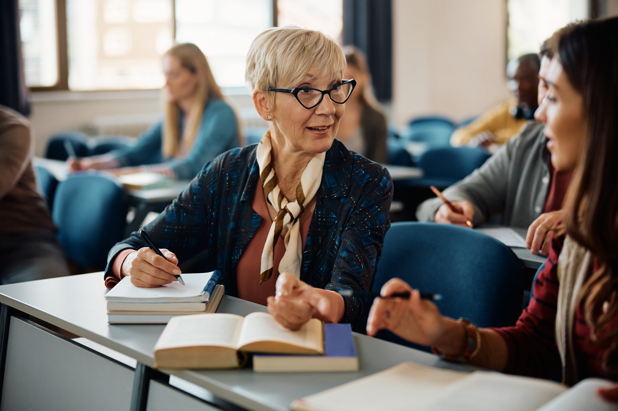 Mature woman speaking with young woman while writing notes Mature woman speaking with young woman while writing notes